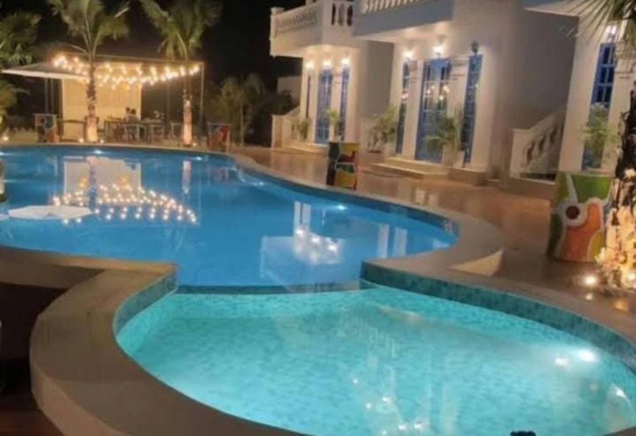 An illuminated swimming pool beside the property at night.